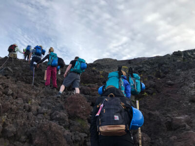 Lines of people slowly hiking up the rocky slopes Hiking up rocks