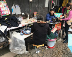 There are many folks out on the street sewing and making repairs. Gaoqiao West Street Sewing repair