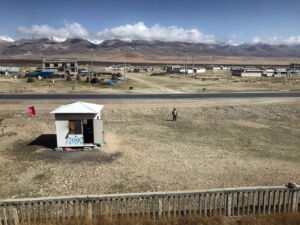A long guard shows respect to the train as it passes. Town somewhere in Tibet
